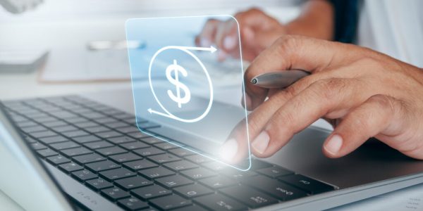 Close-up of hands using a laptop with a dollar sign graphic above the keyboard