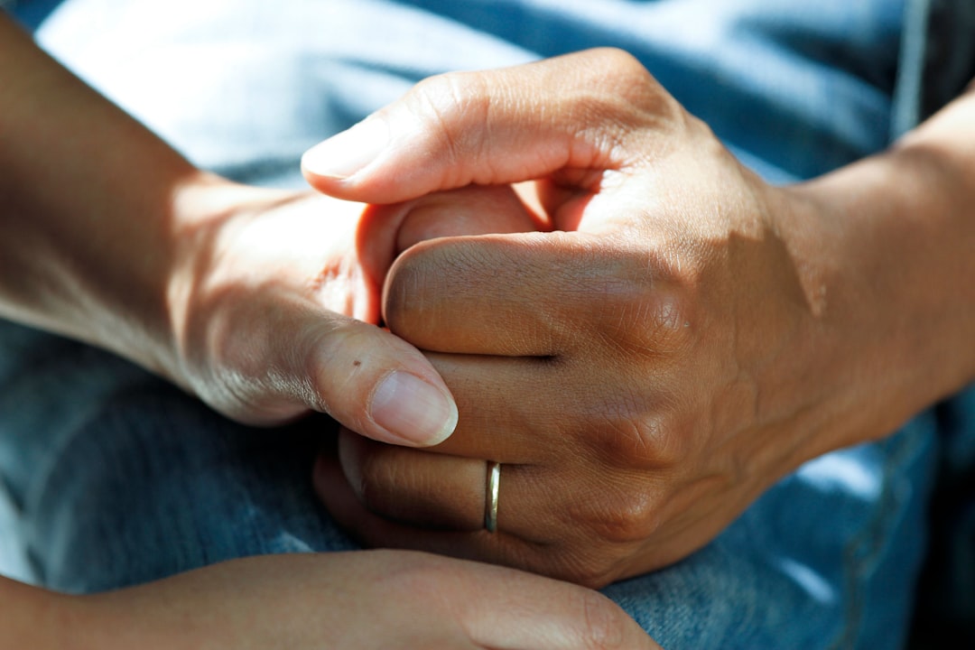 Close-up of two hands clasped together, suggesting support and comfort.